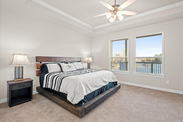 bedroom with ceiling fan, light colored carpet, crown molding, and a tray ceiling