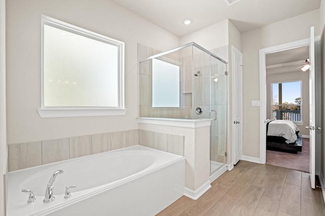 bathroom with ceiling fan, plus walk in shower, and hardwood / wood-style flooring