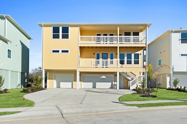 raised beach house with driveway, a balcony, stairway, an attached garage, and a front lawn