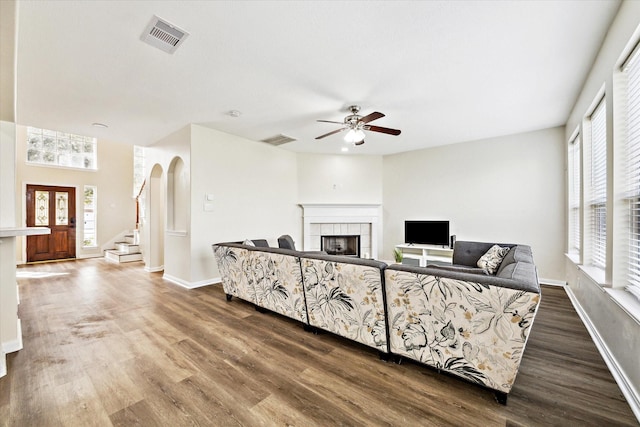 living room featuring a tile fireplace, wood-type flooring, and ceiling fan