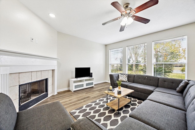 living room with a fireplace, light wood-type flooring, and ceiling fan