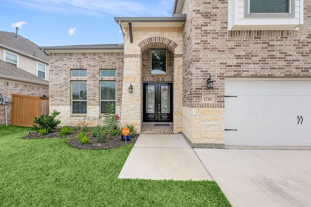 entrance to property with french doors, a garage, and a lawn