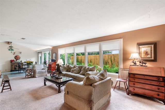 carpeted living room with ceiling fan and a textured ceiling