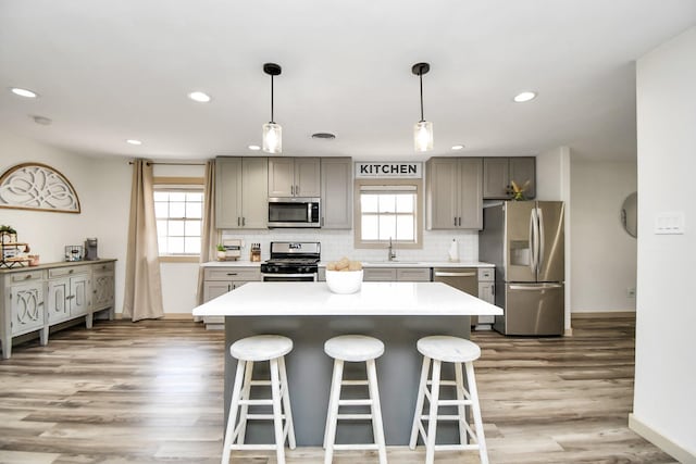 kitchen featuring sink, light hardwood / wood-style flooring, decorative light fixtures, and appliances with stainless steel finishes