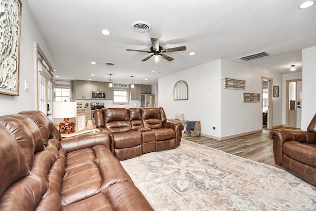 living room with ceiling fan and light hardwood / wood-style flooring