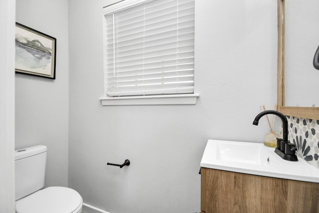 bathroom featuring vanity, backsplash, and toilet