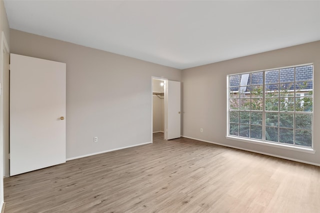 unfurnished bedroom featuring a closet, a spacious closet, and light hardwood / wood-style flooring