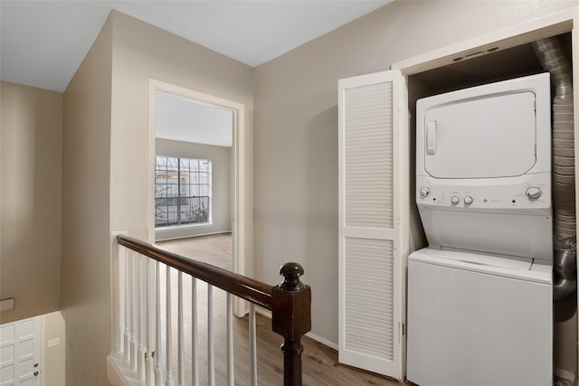 laundry room with light wood-type flooring and stacked washing maching and dryer