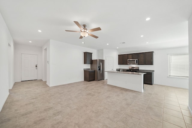 kitchen featuring dark brown cabinetry, a kitchen island with sink, ceiling fan, and stainless steel appliances