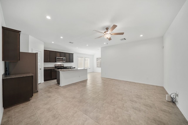 kitchen featuring dark brown cabinets, stainless steel appliances, ceiling fan, and an island with sink