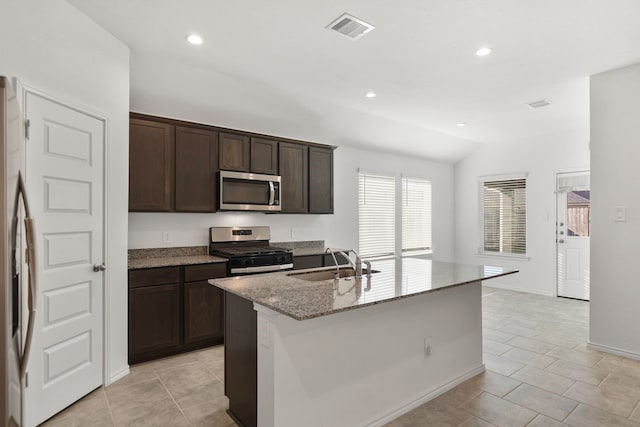 kitchen featuring light stone counters, sink, an island with sink, and appliances with stainless steel finishes