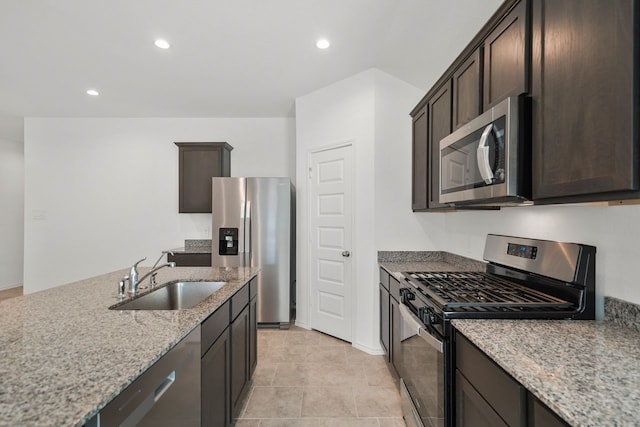 kitchen featuring light stone countertops, dark brown cabinetry, stainless steel appliances, sink, and light tile patterned flooring