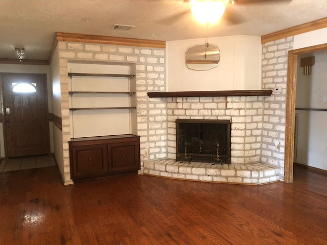 unfurnished living room featuring crown molding, ceiling fan, dark wood-type flooring, and a brick fireplace