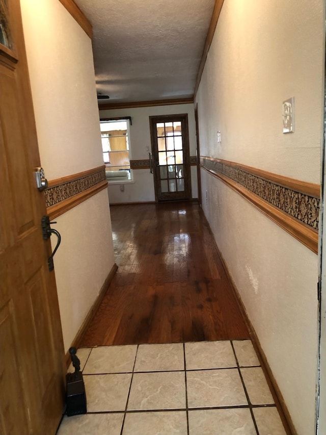 hallway featuring wood-type flooring, a textured ceiling, and ornamental molding