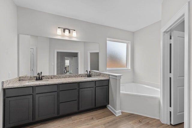 bathroom featuring hardwood / wood-style floors, vanity, and a tub