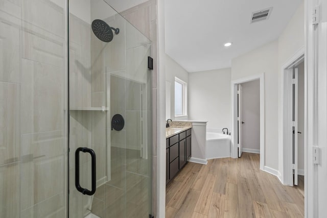 bathroom with hardwood / wood-style floors, vanity, and shower with separate bathtub