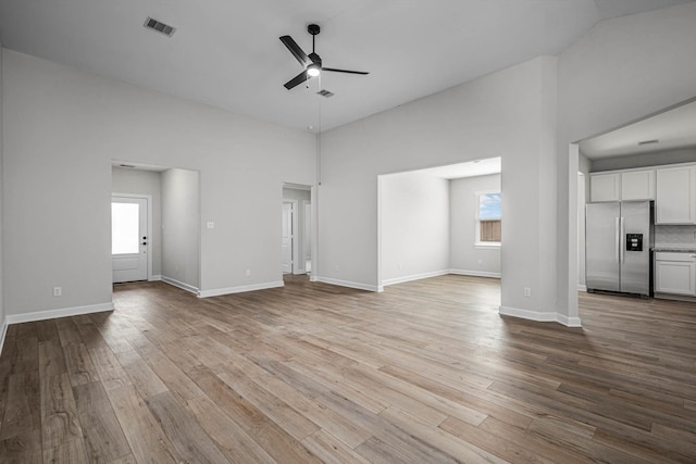 unfurnished living room with light wood-type flooring, high vaulted ceiling, and ceiling fan