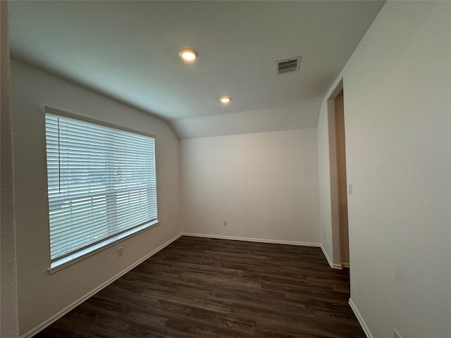 spare room with dark hardwood / wood-style flooring and vaulted ceiling