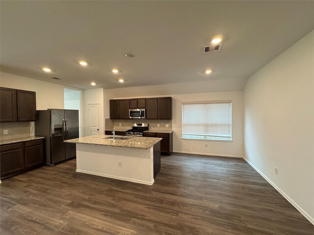 kitchen featuring light stone counters, stainless steel appliances, sink, a center island with sink, and dark hardwood / wood-style floors