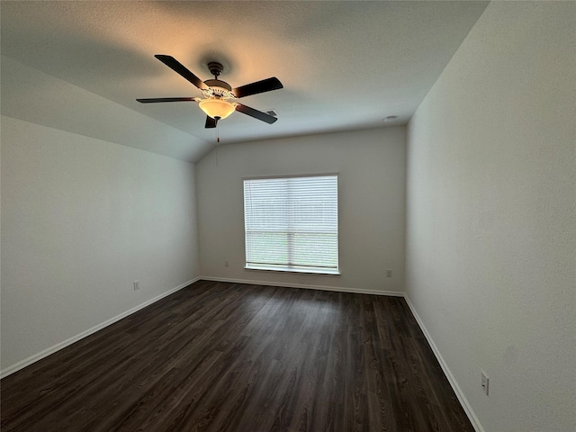 spare room featuring dark hardwood / wood-style floors, vaulted ceiling, and ceiling fan