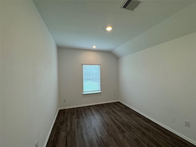 spare room with dark hardwood / wood-style flooring and vaulted ceiling