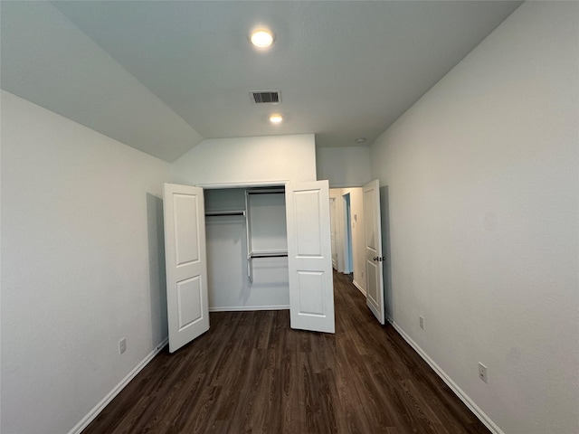 unfurnished bedroom with vaulted ceiling, a closet, and dark hardwood / wood-style floors