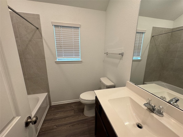 full bathroom featuring tiled shower / bath, hardwood / wood-style floors, vanity, and toilet