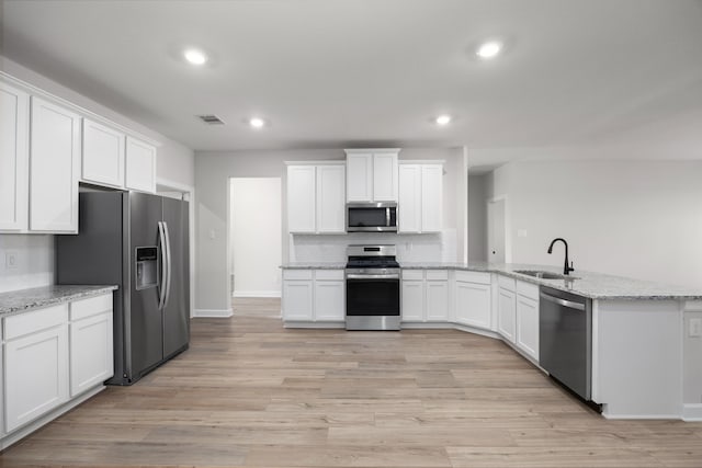 kitchen featuring white cabinetry, sink, light stone counters, and appliances with stainless steel finishes