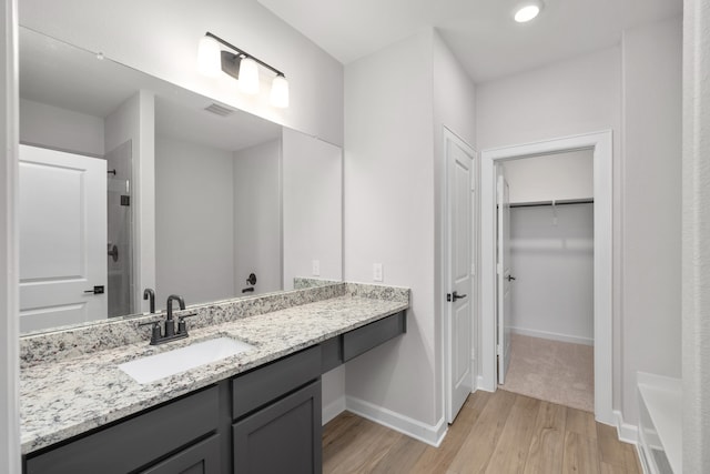 bathroom featuring hardwood / wood-style flooring, vanity, and walk in shower