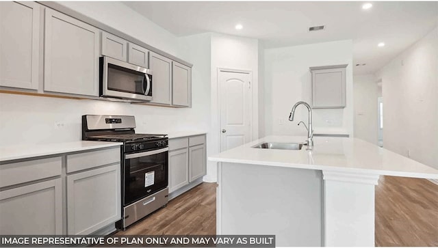 kitchen featuring visible vents, a sink, appliances with stainless steel finishes, a center island with sink, and gray cabinets