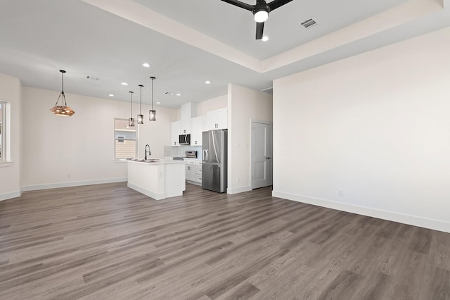 unfurnished living room with hardwood / wood-style flooring, ceiling fan, and sink