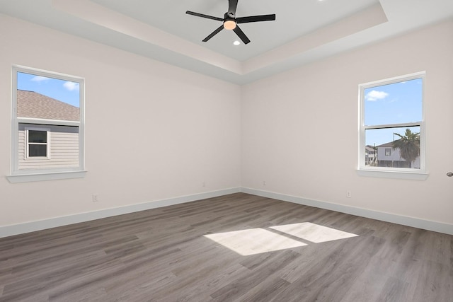 unfurnished room with a tray ceiling, ceiling fan, and hardwood / wood-style floors