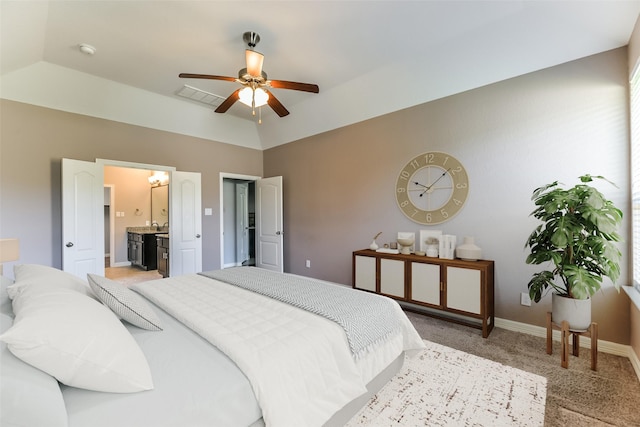 bedroom featuring ceiling fan, ensuite bath, vaulted ceiling, and light carpet