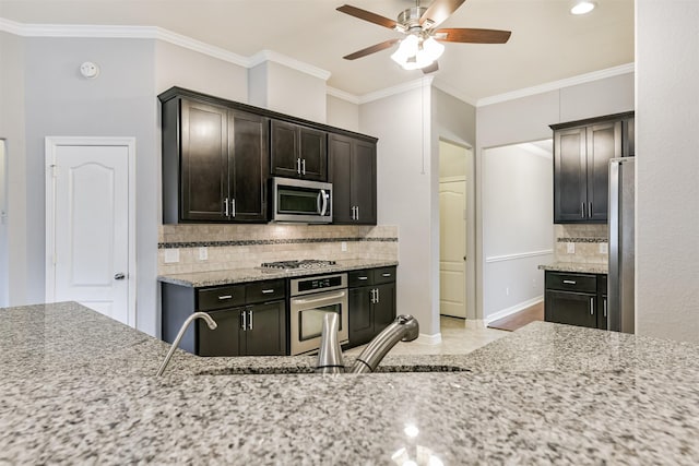 kitchen with ceiling fan, appliances with stainless steel finishes, tasteful backsplash, dark brown cabinets, and light stone countertops