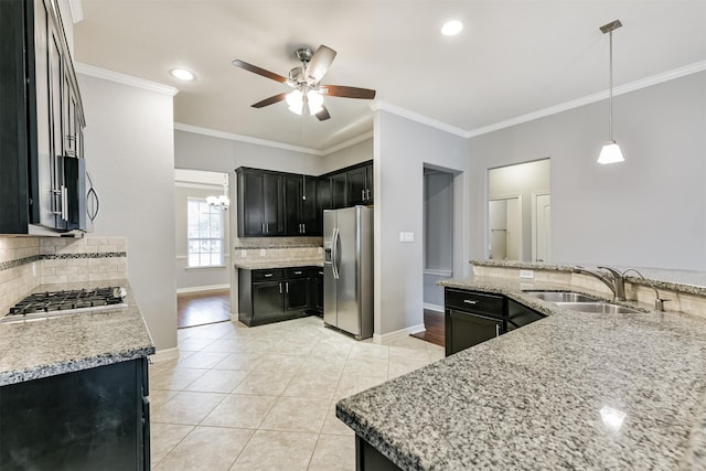 kitchen featuring decorative backsplash, sink, hanging light fixtures, light stone countertops, and appliances with stainless steel finishes