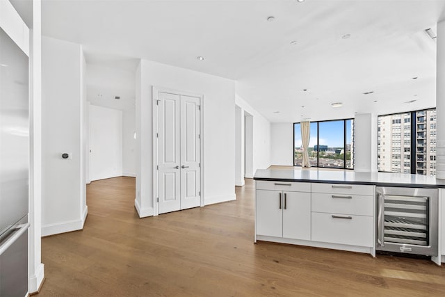 kitchen with wine cooler, white cabinets, stainless steel built in refrigerator, and light wood-type flooring