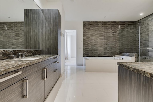 bathroom with tile patterned floors, a tub to relax in, vanity, and tile walls