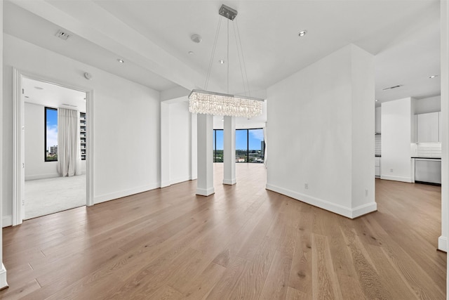 unfurnished living room with a chandelier and light wood-type flooring