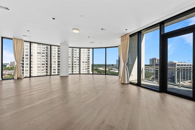 spare room featuring a wealth of natural light, floor to ceiling windows, and wood-type flooring