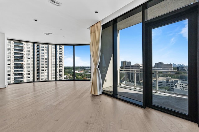 empty room with hardwood / wood-style floors and a wall of windows