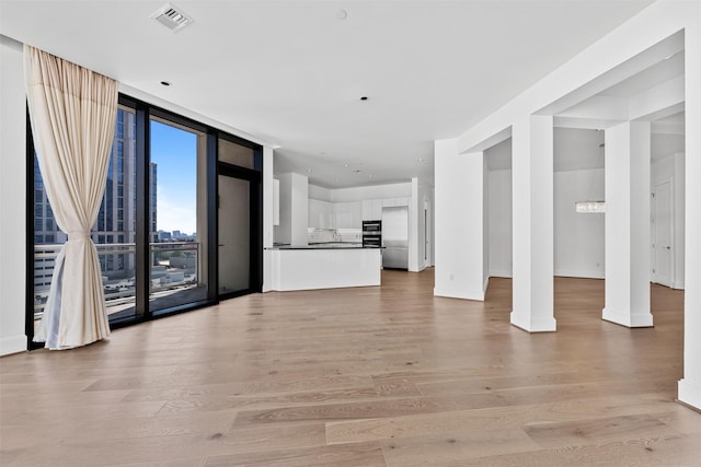 unfurnished living room with light wood-type flooring and expansive windows