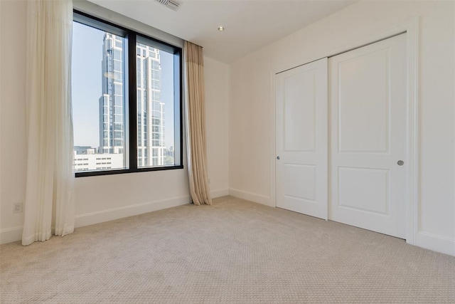 unfurnished bedroom with light colored carpet and a closet