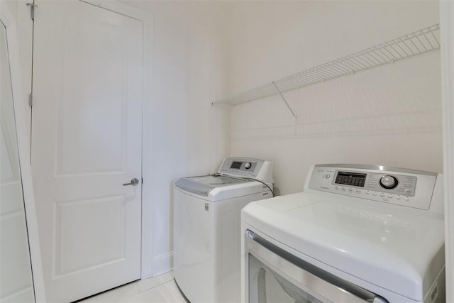 laundry room featuring washer and clothes dryer and light tile patterned flooring