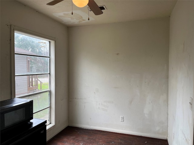 empty room with a wood stove, baseboards, and a ceiling fan