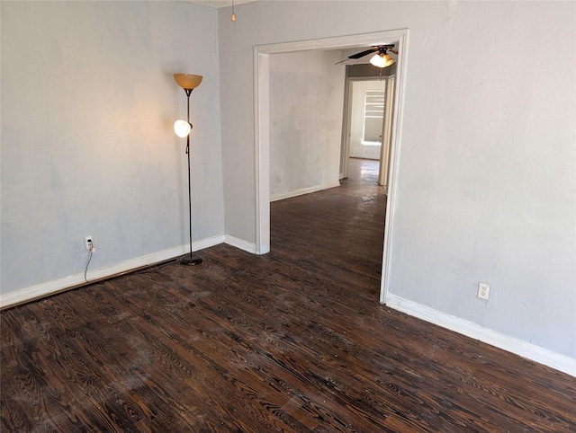 spare room with baseboards, a ceiling fan, and dark wood-style flooring