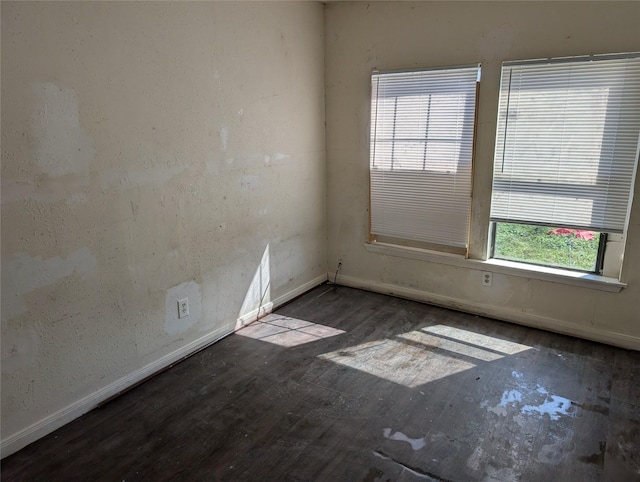 spare room with baseboards and wood finished floors