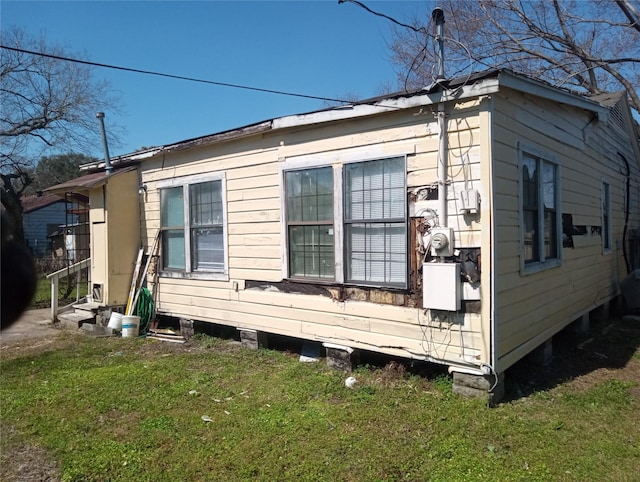 view of side of home featuring entry steps and a lawn