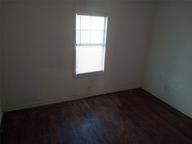 unfurnished room featuring dark wood-type flooring and baseboards