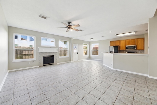 unfurnished living room featuring ceiling fan, light tile patterned floors, and a high end fireplace