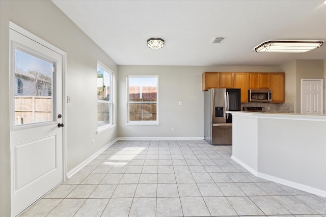 kitchen featuring decorative backsplash, light tile patterned flooring, and appliances with stainless steel finishes